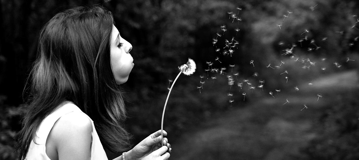 Femme souffle sur un pissenlit